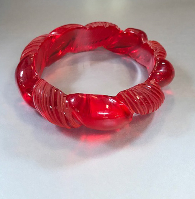 BAKELITE red transparent rope carved bangle with alternating segments of carved and plain areas