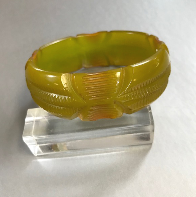 BAKELITE translucent green carved bangle that has peach colored tints at the edges