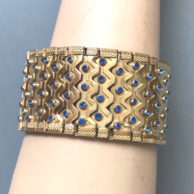 DEROSA bracelet with lots of brilliant blue rhinestones in a wide shimmering gold plated setting with a geometric zigzag design