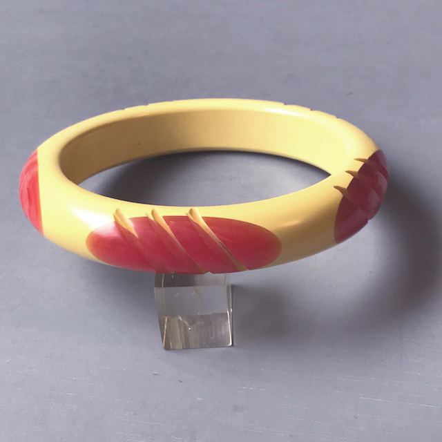 PANTTI bakelite cream colored bangle with four long oval rose pink dots that are carved through in a diagonal pattern